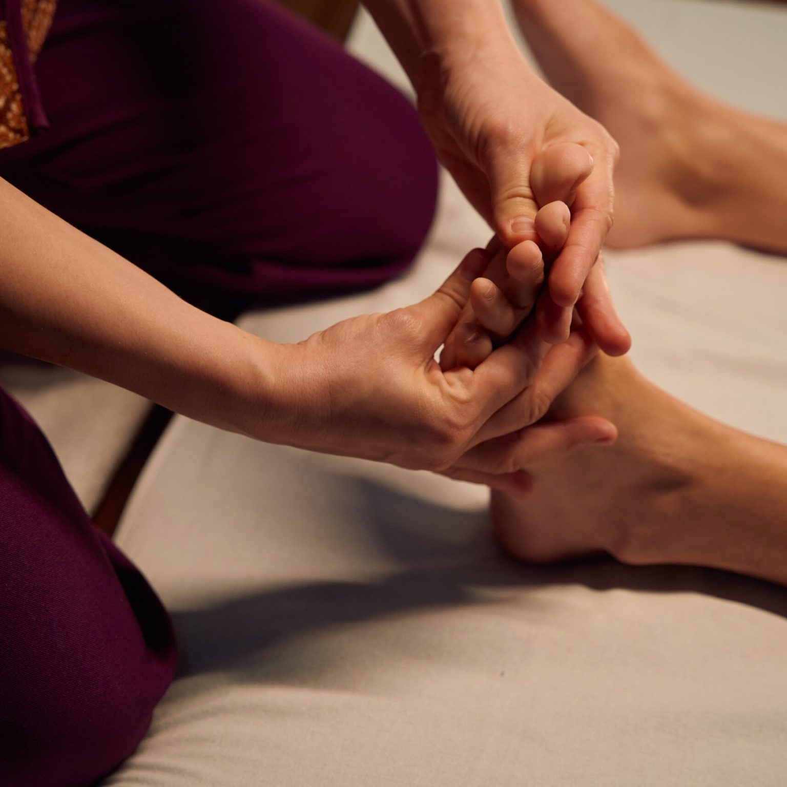 Licensed massotherapist performing traditional Thai foot massage to woman